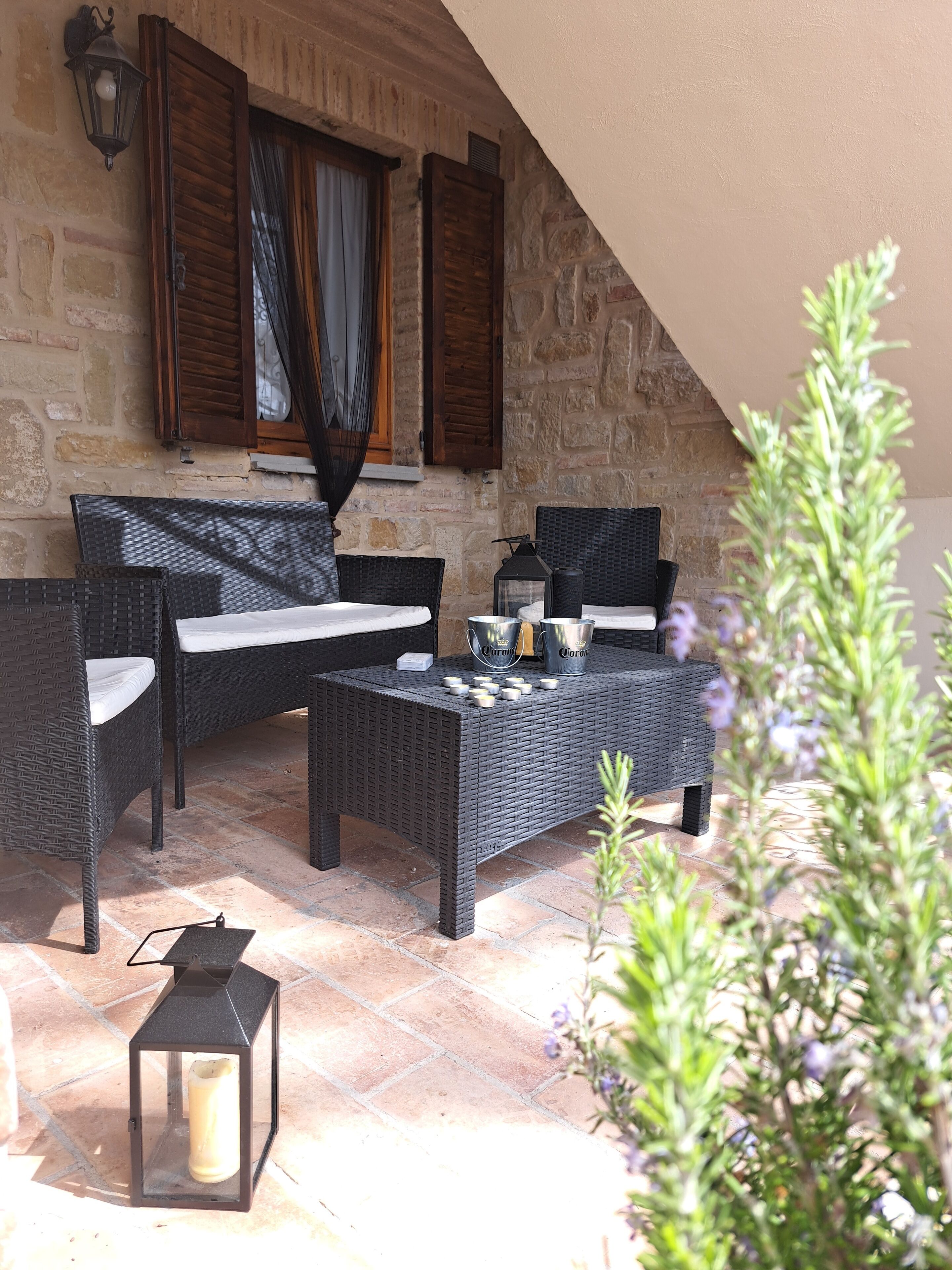 Eine Terrassenanlage mit Korbmöbeln, einem Tisch mit Kerzen und einem Laternen.