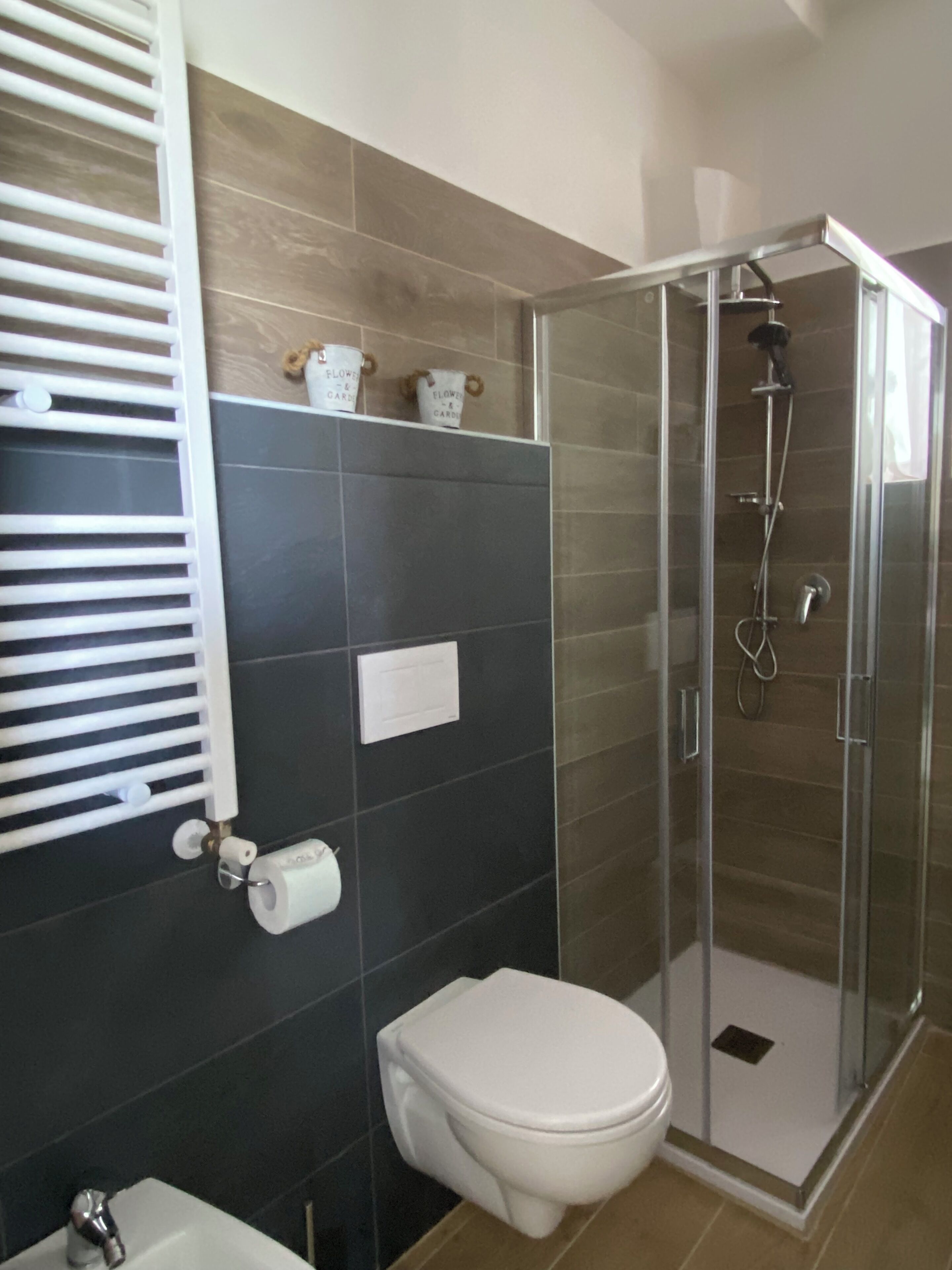 Un baño con inodoro, cabina de ducha y un perchero para toallas.