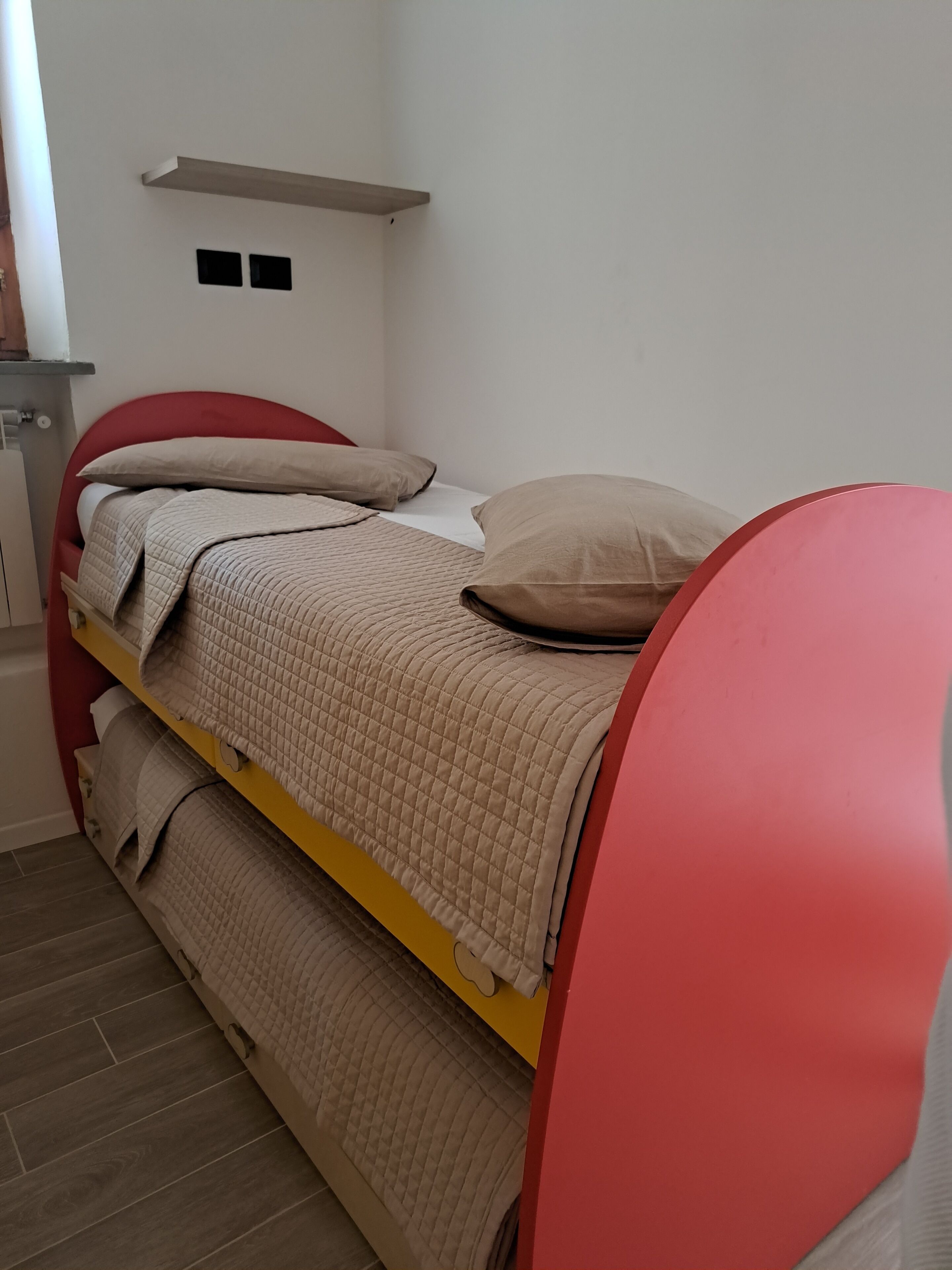 A bunk bed with a red headboard and beige bedding.