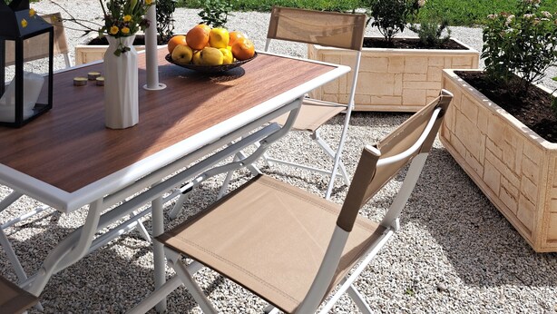 An outdoor patio with a table and chairs, a large umbrella, and a scenic view of rolling hills.