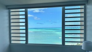 A room with a window overlooking a turquoise sea and clear sky.