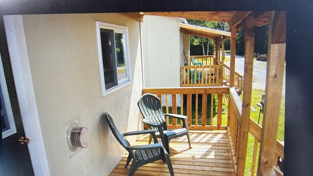 A wooden deck with two Adirondack chairs, a window, and a door.