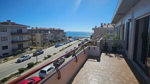 A balcony with a view of a street and sea.