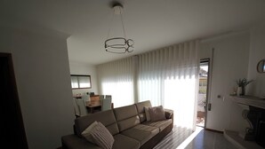 A living room with a sofa, a dining table, and a chandelier.