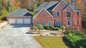 A two-story brick house with a garage, a well-maintained lawn, and a driveway. - STAR MANSION ATLANTA (Atlanta)