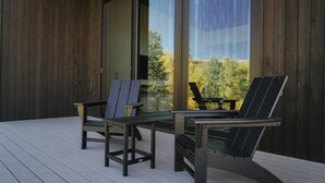 Terraza con dos sillas Adirondack y una mesita, con vistas a un paisaje natural.