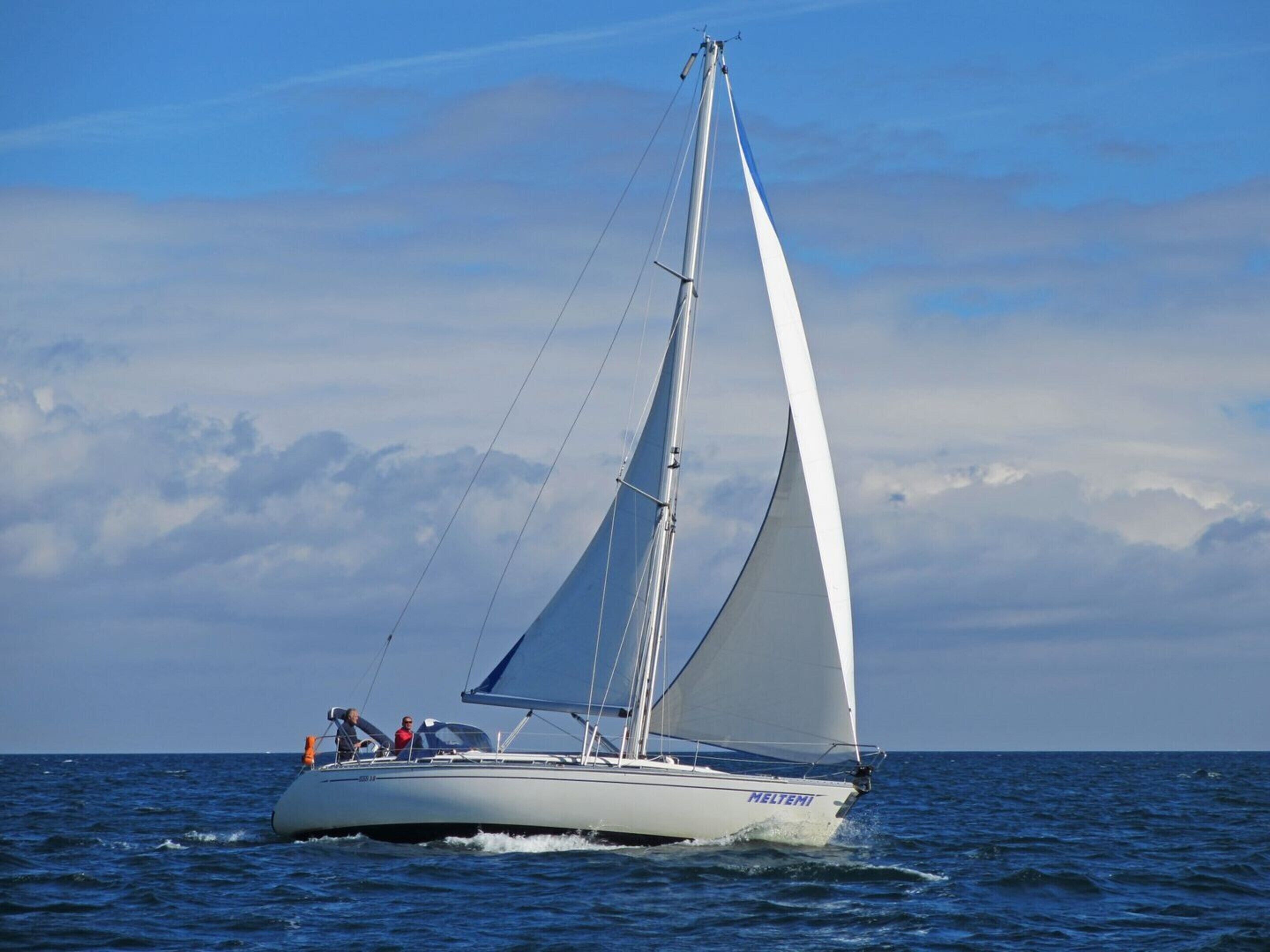 Eine Segelyacht mit dem Namen "HELTEMI" auf der Seite, die auf dem Wasser fährt.