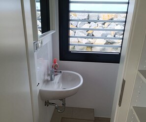 A small bathroom with a white sink, a window with a view of rocks, and a mirror. - Hausboot in Laboe an der Kieler Foerde (Laboe)