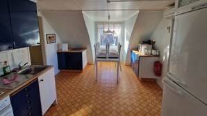 A kitchen with a tiled floor, a refrigerator, a sink, cabinets, and a window with curtains. - Vacation apartment Fagerhult (Kalmar län)