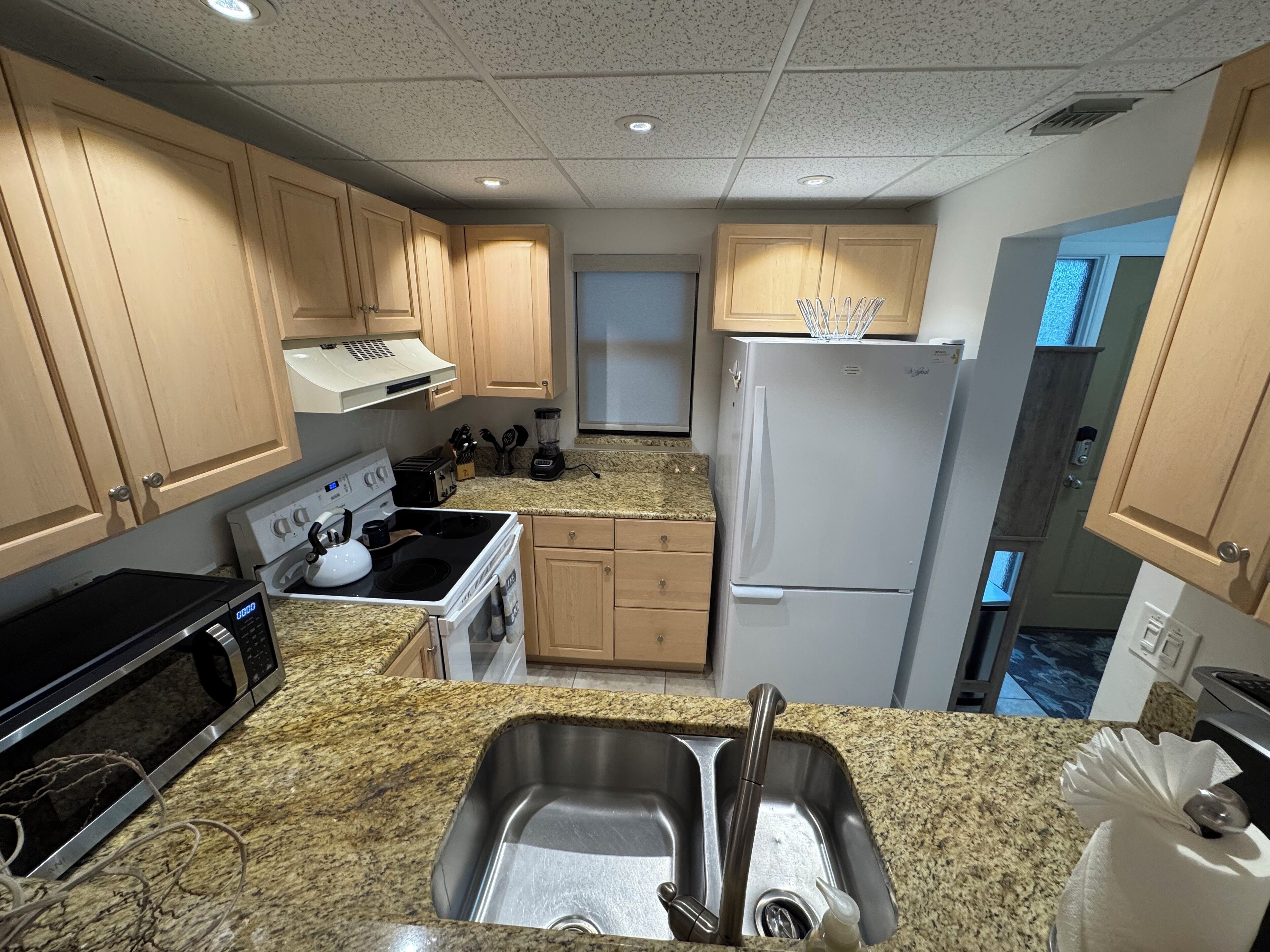 A compact kitchen with a stove, microwave, sink, and a refrigerator.