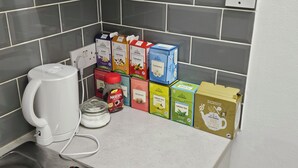 A kitchen counter with a coffee maker, a jar of jam, and various tea boxes. - Modern Spacious Flat 10 Minutes from Big Ben (London)