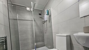 A modern bathroom with a glass-enclosed shower, a white toilet, and a sink. - Modern Spacious Flat 10 Minutes from Big Ben (London)