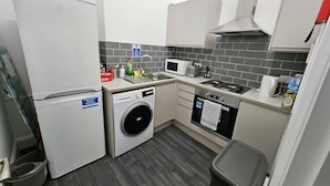 A compact kitchen with a washing machine, microwave, and oven. - Modern Spacious Flat 10 Minutes from Big Ben (London)