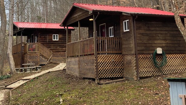 A cabin with a red roof, wooden exterior, and a porch with a railing. - Cozy & efficient cabin w/ river access. Pet Friendly! (Stanton)