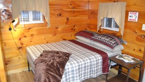 A wooden cabin room with a bed, a nightstand, and a window with a 'Please No Inside' sign. - Cozy & efficient cabin w/ river access. Pet Friendly! (Stanton)