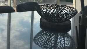 Een kamer met een groot raam, een glazen tafel en een decoratieve zwarte kom.