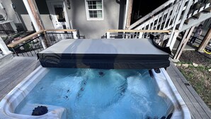 A hot tub on a wooden deck with a white exterior wall and a window in the background. - Barndominium getaway oasis! Close to Chattanooga shopping restaurants and Water! (Apison)