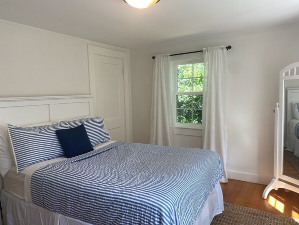 Une chambre à coucher avec un lit, une fenêtre avec des rideaux et une armoire blanche.