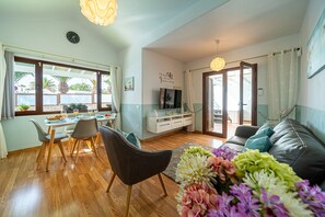 Relax in this open-plan living space with a dining area and seating area, featuring a large window with a garden view.