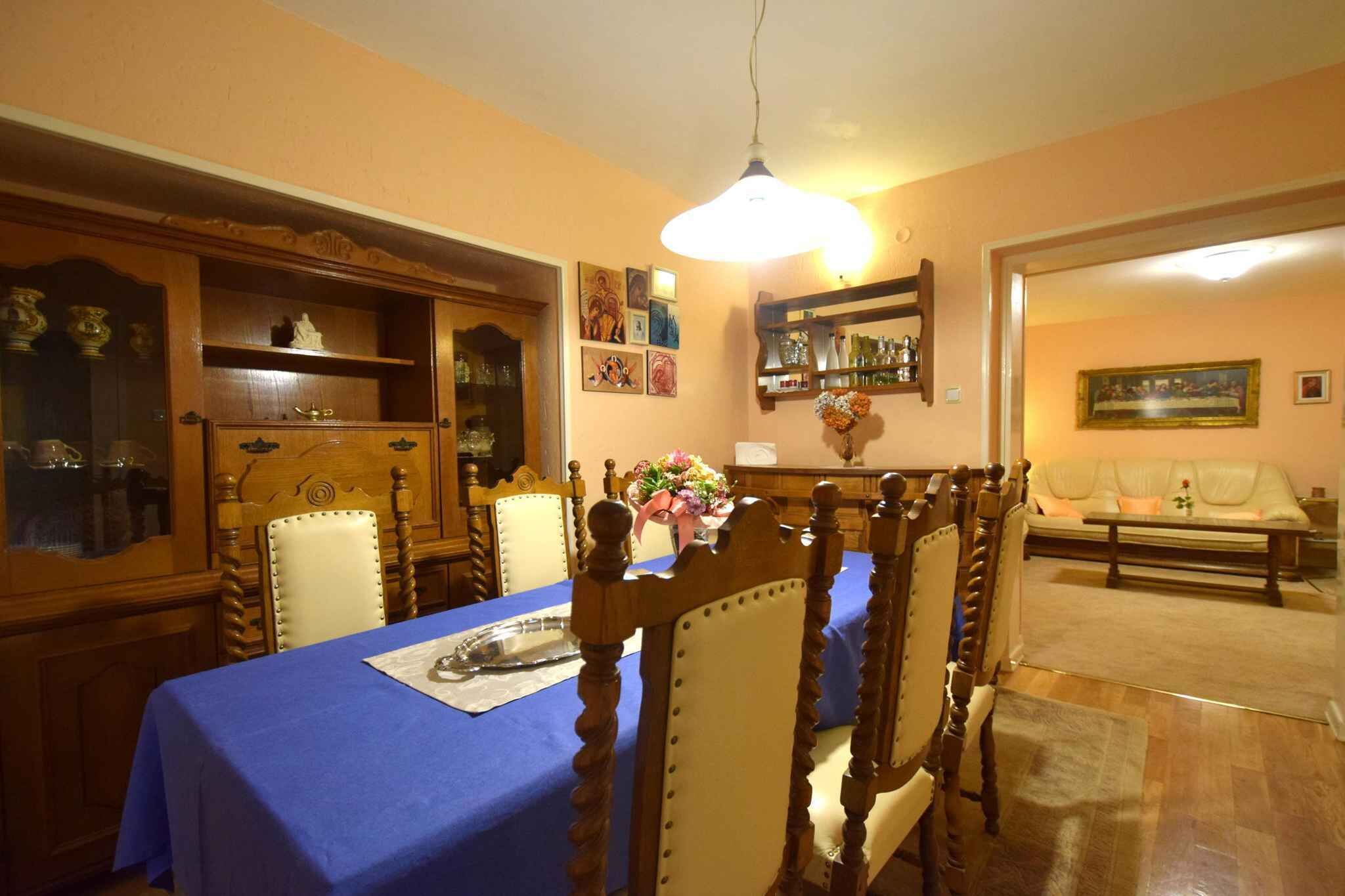 Un coin repas avec une nappe bleue, des chaises en bois et un lustre.