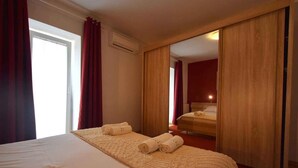 Una camera d'albergo con un letto, uno specchio e una porta scorrevole.
