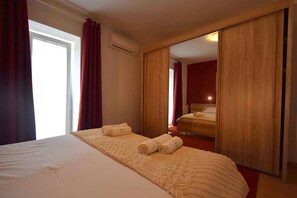 A hotel room with a bed, a mirror, and a sliding door.