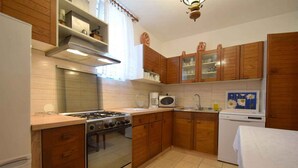 Cucina con mobili in legno, piano cottura, forno a microonde ed elettrodomestici.