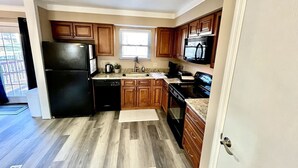 A kitchen with wooden cabinets, a black refrigerator, a dishwasher, and a microwave. - Spacious 3 Bedroom with Outdoor Pool in Mason (Mason)