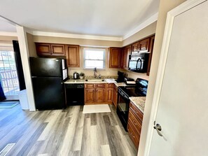 A kitchen with wooden cabinets, a black refrigerator, a dishwasher, and a microwave. - Spacious 3 Bedroom with Outdoor Pool in Mason (Mason)