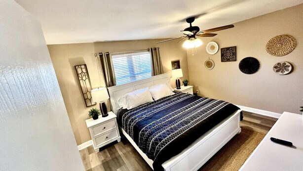 A bedroom with a bed, bedside tables, a nightstand, a ceiling fan, and wall decor. - Spacious 3 Bedroom with Outdoor Pool in Mason (Mason)
