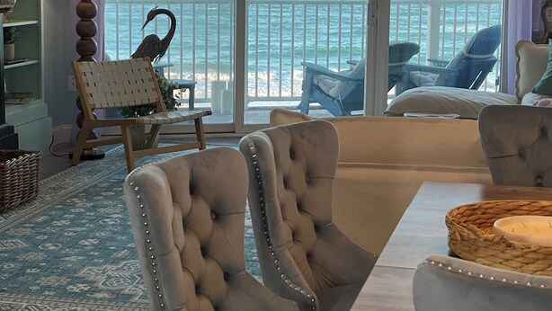 Ein Zimmer mit Meerblick, ausgestattet mit einem Essbereich, einem Tisch, Stühlen, einer Couch und einem Sessel mit Zierleiste.