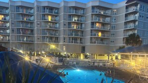 Ein Schwimmbecken mit Blick auf ein mehrstöckiges Hotelgebäude im Hintergrund.
