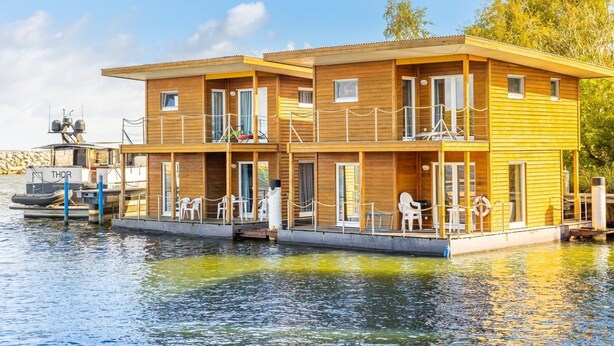 Un hotel flotante de varios niveles, con asientos al aire libre y un barco amarrado.