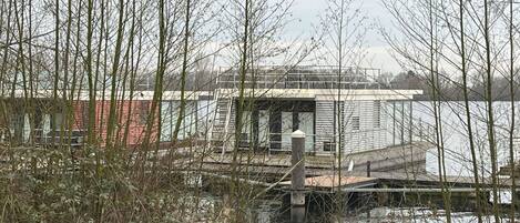 A waterfront house with a dock, surrounded by trees and a body of water.
