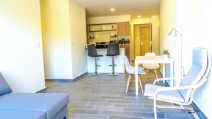 A compact living space with a kitchenette, a dining area with a table and chairs, and a sofa.