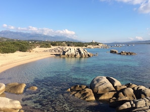 A coastal landscape with clear waters, rocky formations, and a distant castle on a hill. - VILLA with ocean views, a beautiful pool, and a fenced-in garden, located on the coast of southern Corsica (Pianottoli-Caldarello)
