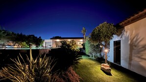 A modern house with a well-lit garden at night, featuring a swimming pool, a patio, and a large tree. - VILLA Sea View with beautiful swimming pool and enclosed garden, seaside SOUTH CORSICA   (Pianottoli-Caldarello)