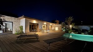 Et moderne hus med træterrasse, udendørs møbler og swimmingpool.