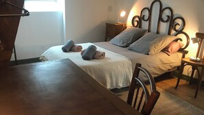 Un lit bien fait, avec des oreillers et des serviettes enroulées, une table de chevet avec une lampe et une chaise en bois.