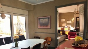 Un coin repas comprenant une table ronde, des chaises, un vase avec des fleurs et un plan de travail rouge agrémenté d’une planche à découper et d’un panier.