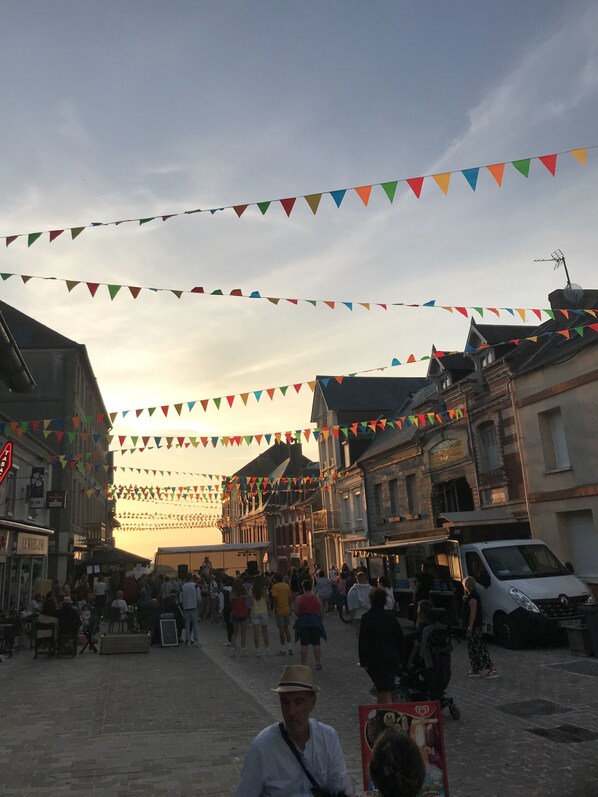 A bustling street with historic buildings, a crowd of people, and colorful triangular flags. - 15-person gîte in the Baie de Somme, ideal for family reunions!  (Ault)