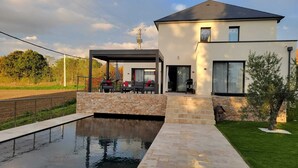 A modern house with a swimming pool, outdoor seating, and a stone wall. - Just 15 minutes from the 24 Hours of Le Mans racetrack! Ideal for 10 people (Pruillé-le-Chétif)