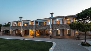 A large, multi-story house with stone arches and a well-maintained lawn.