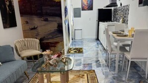 A living room with a glass coffee table, a sofa, and a dining area with a white table and chairs.