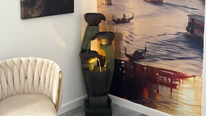 A room with a mural of a cityscape, a chair, and a decorative water feature.