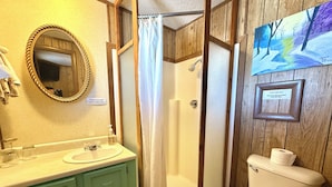 A bathroom with a shower, toilet, sink, and a mirror. - Short Branch Motel (Pahrump)