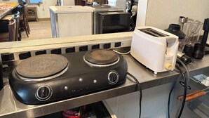 A kitchen with a stove, toaster, and various appliances. - Short Branch Motel (Pahrump)