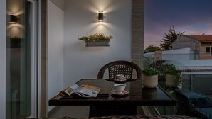 Un balcón con mesa, sillas y una planta en maceta.