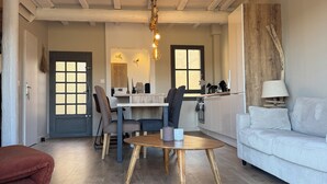 Amplia sala de estar con piso de madera, un comedor con mesa redonda y una cocina al fondo.