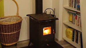 Ein Zimmer mit einem schwarzen Kaminofen, einem Korbwäsche und einem Bücherregal mit Büchern und Dekoration.